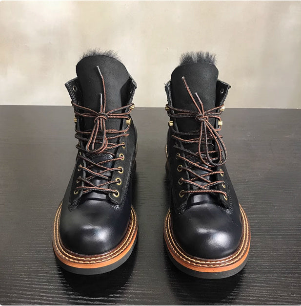 Pair of black leather boots with brown laces and soles on a dark surface.