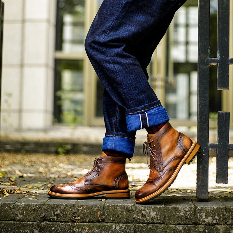 Person wearing brown leather boots and blue jeans standing on a stone path.