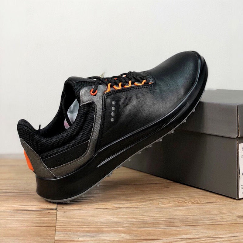 Black leather shoe with orange accents on a wooden surface