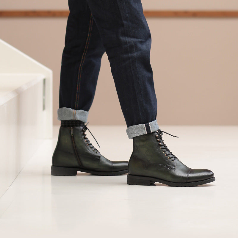 Person wearing black leather boots and dark jeans on a light floor.