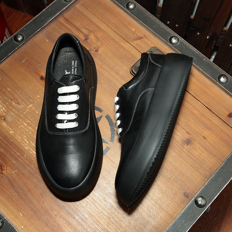 Pair of black shoes with white laces on a wooden surface