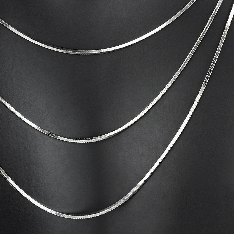 Three silver chains of different thicknesses on a black background