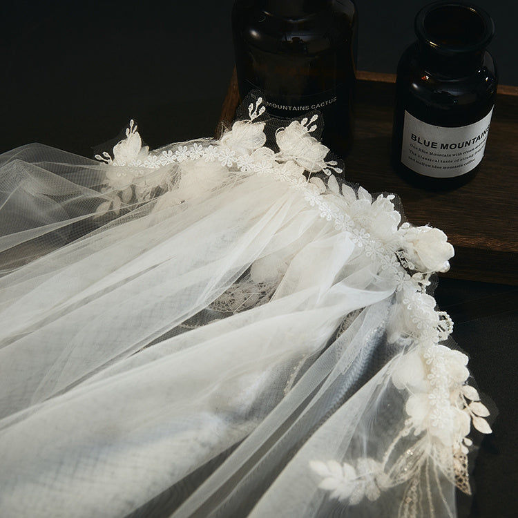 White lace veil with floral details on a dark surface with 'Blue Mountain' coffee beans in the background.