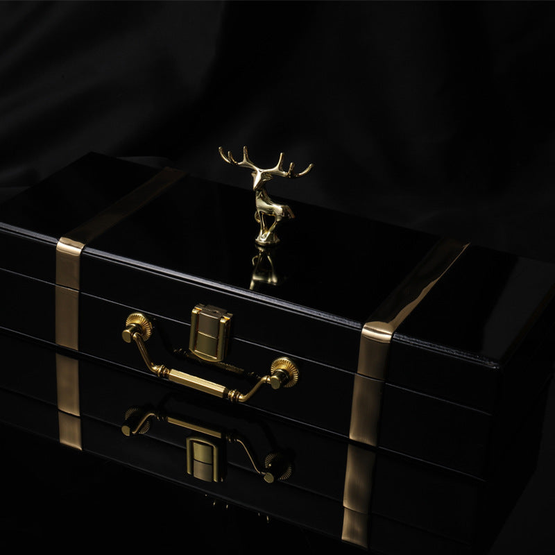 Black jewelry box with gold accents and a deer figurine on a black background