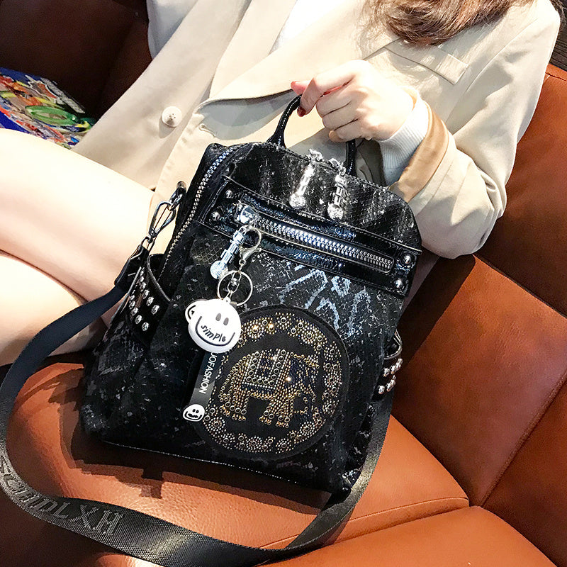 Black glittery handbag with decorative elements held by a person on an orange couch.
