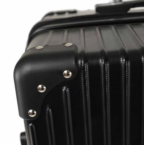 Close-up of a black suitcase with metallic accents on a white background