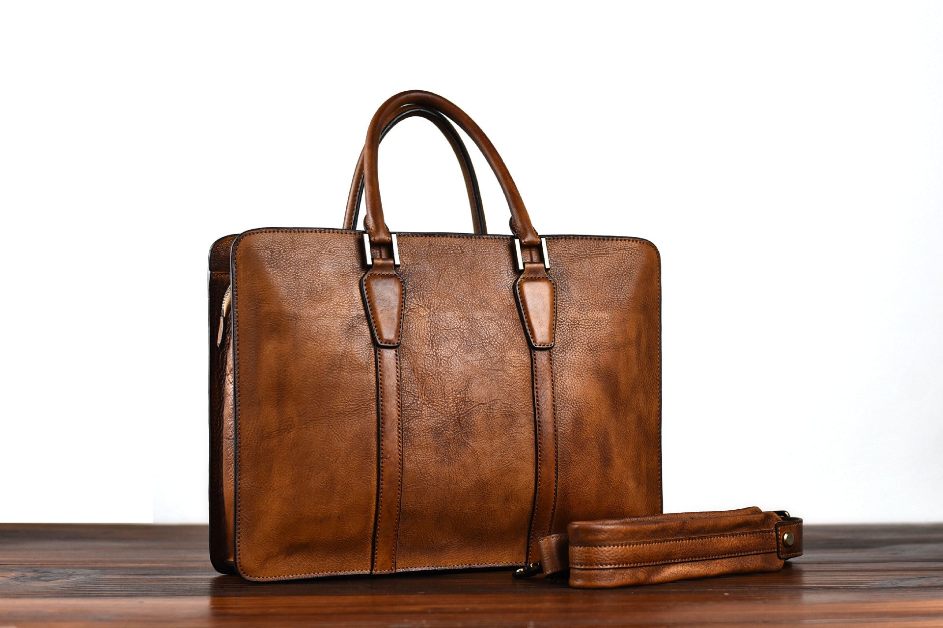 Brown leather briefcase on a wooden surface with a white background