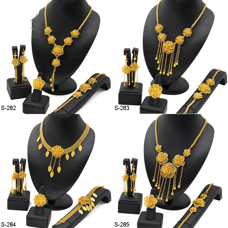 Gold jewelry set including necklace, earrings, and bracelet on black stands.