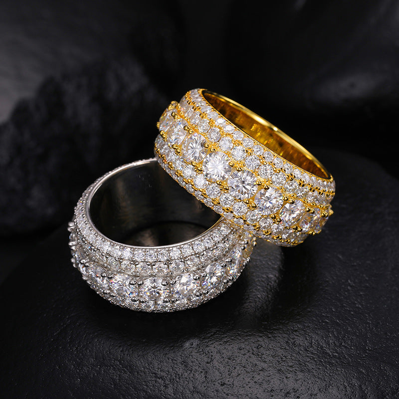 Two diamond-encrusted rings, one gold and one silver, on a dark textured surface.