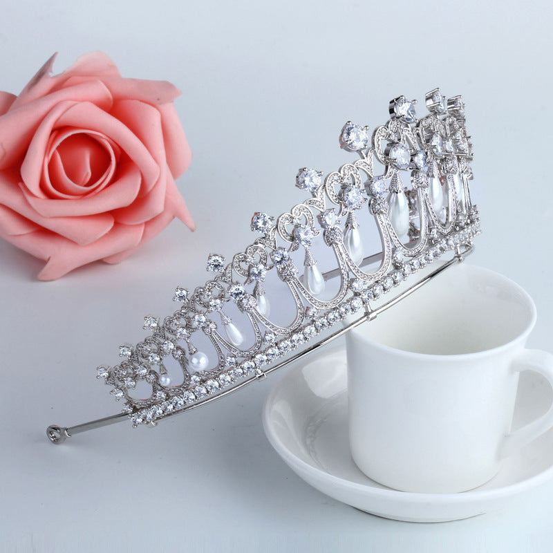 Silver tiara on a white cup with a pink rose in the background