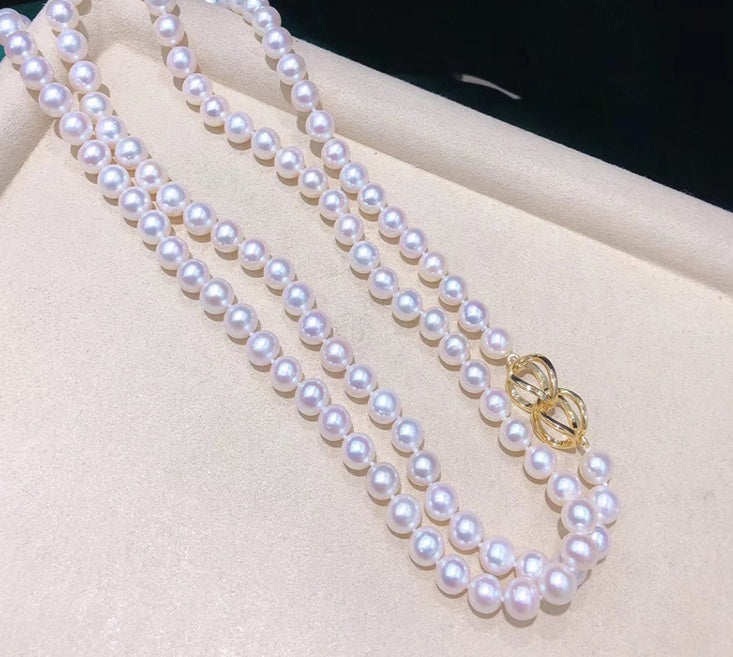 Pearl necklace with a gold clasp on a white surface