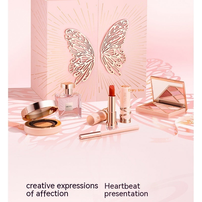 Makeup products including a compact, lipstick, and perfume on a pink background with butterfly wings.
