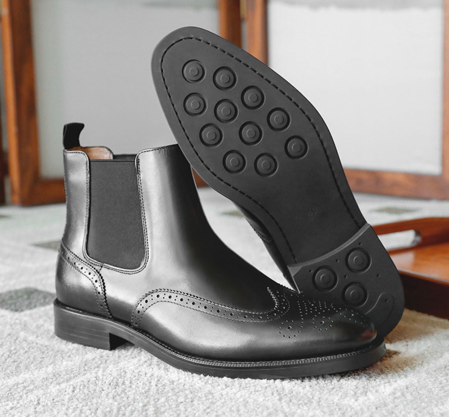 Black leather Chelsea boot with a focus on the sole and tread pattern.