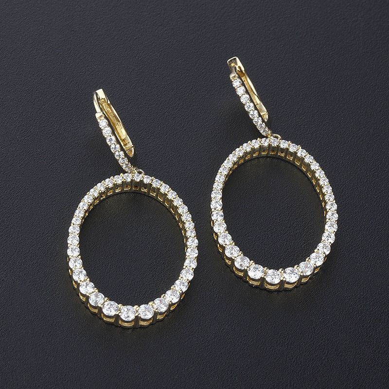 Gold hoop earrings with diamond accents on a dark background