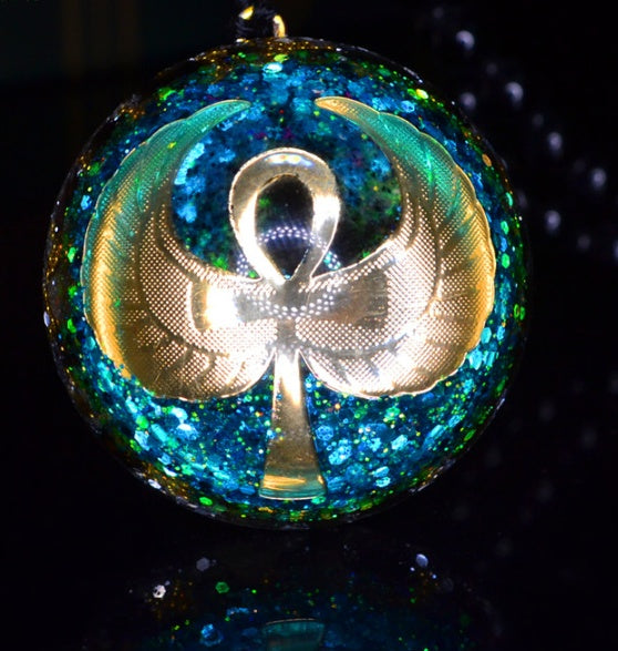 Decorative ornament with a gold ankh symbol on a blue glittery background