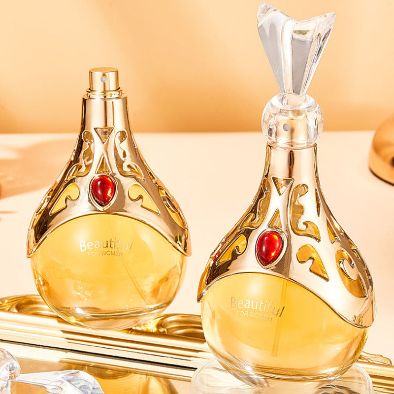 Two ornate perfume bottles with gold accents and red gemstones on a reflective surface.