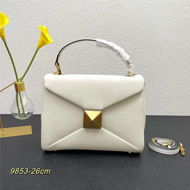 White handbag with gold accents on a dark surface with a light gray background