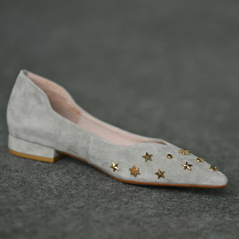 Gray suede flat shoe with gold star embellishments on a dark gray background