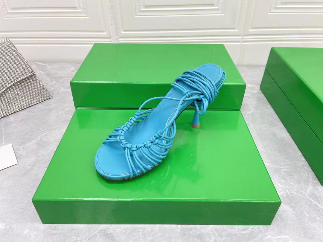 Blue sandal on a green platform with a white textured background