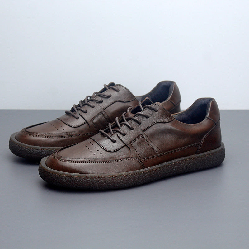 Pair of brown leather shoes on a gray surface with a light gray background