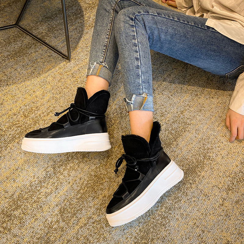 Person wearing black sneakers with white soles on a textured floor.