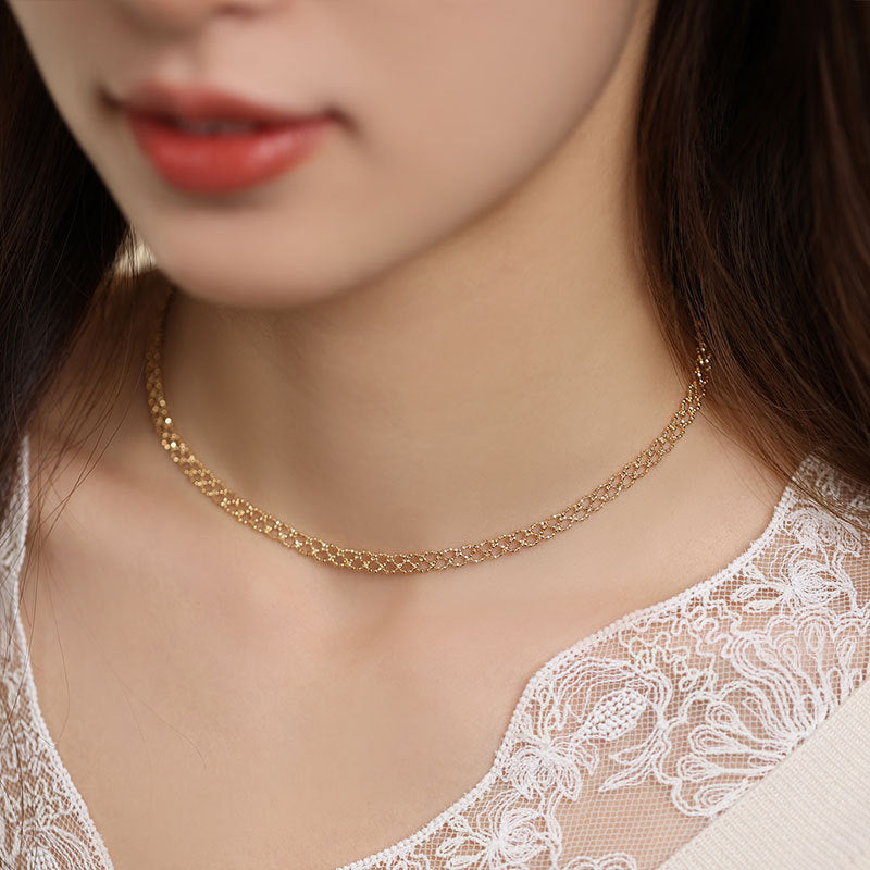 Close-up of a person wearing a gold necklace with a blurred background