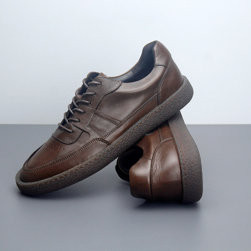 Pair of brown leather shoes on a gray surface with a light gray background