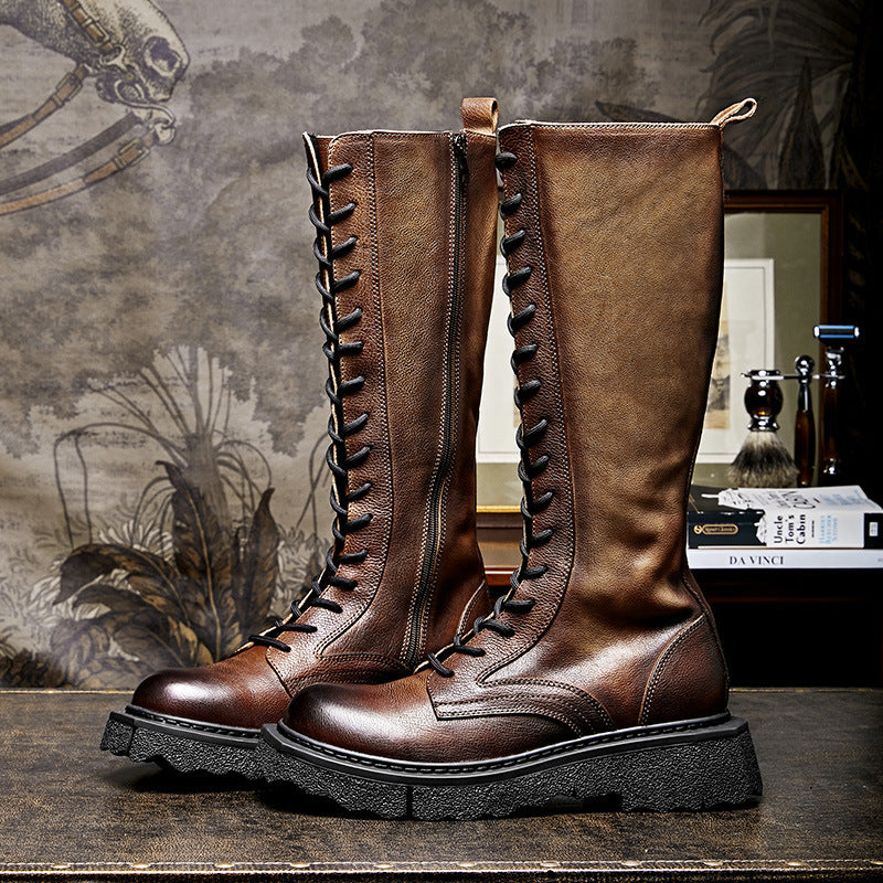 Pair of brown leather knee-high boots with black laces on a textured surface.