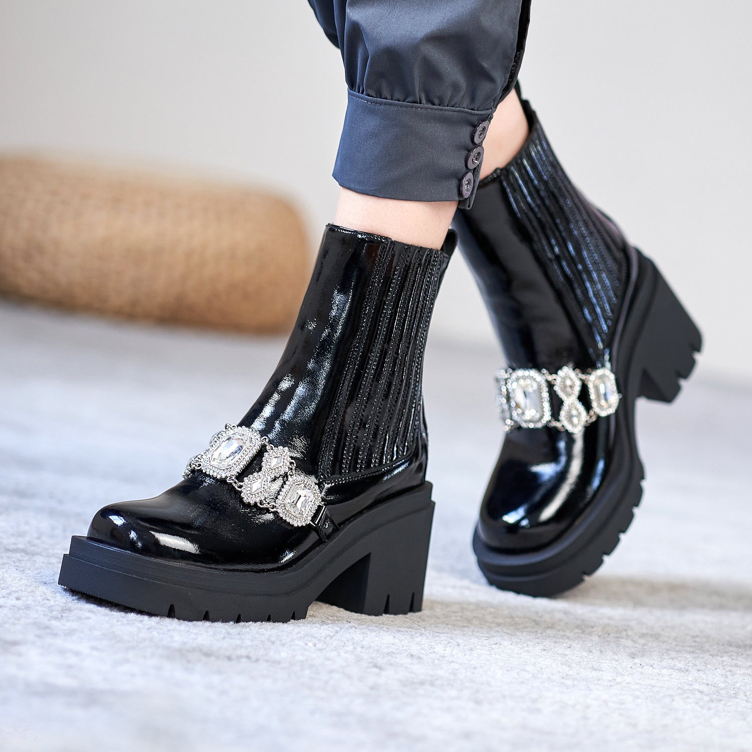 Black platform boots with decorative straps worn by a person on a light background