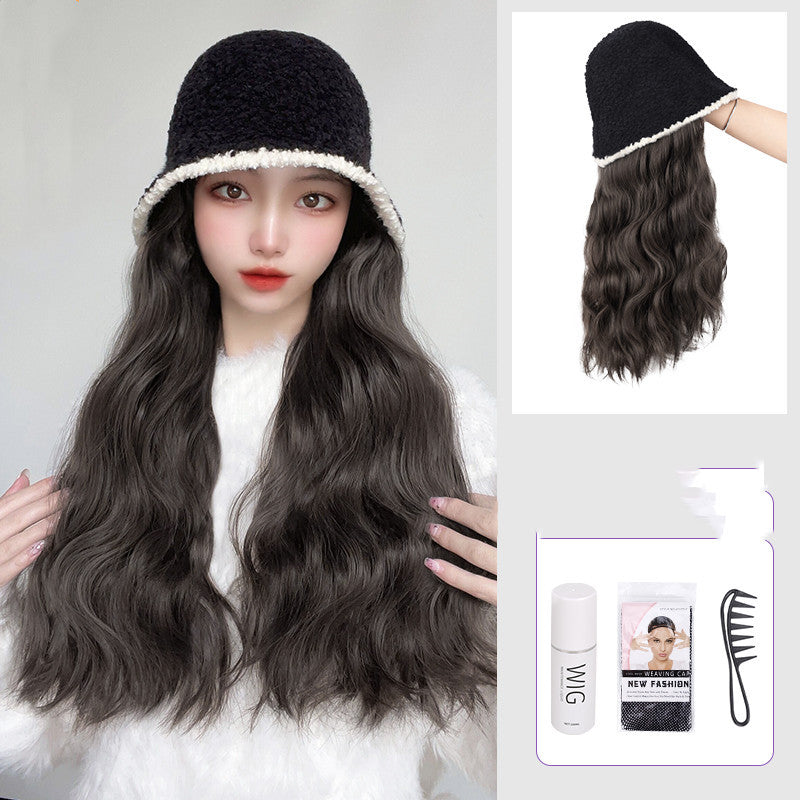 Woman wearing a black hat with a white rim, long wavy gray wig, and a bottle of wig care product.