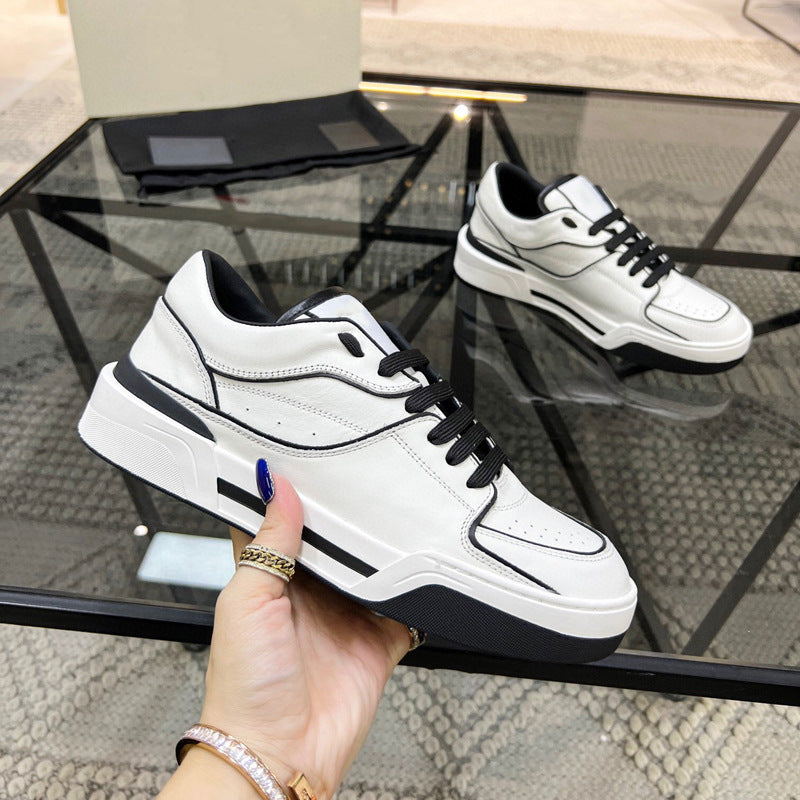 White and black sneakers held by a hand with a glass table in the background