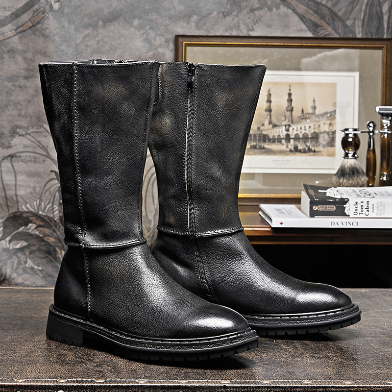Pair of black leather boots on a textured surface with a decorative background.