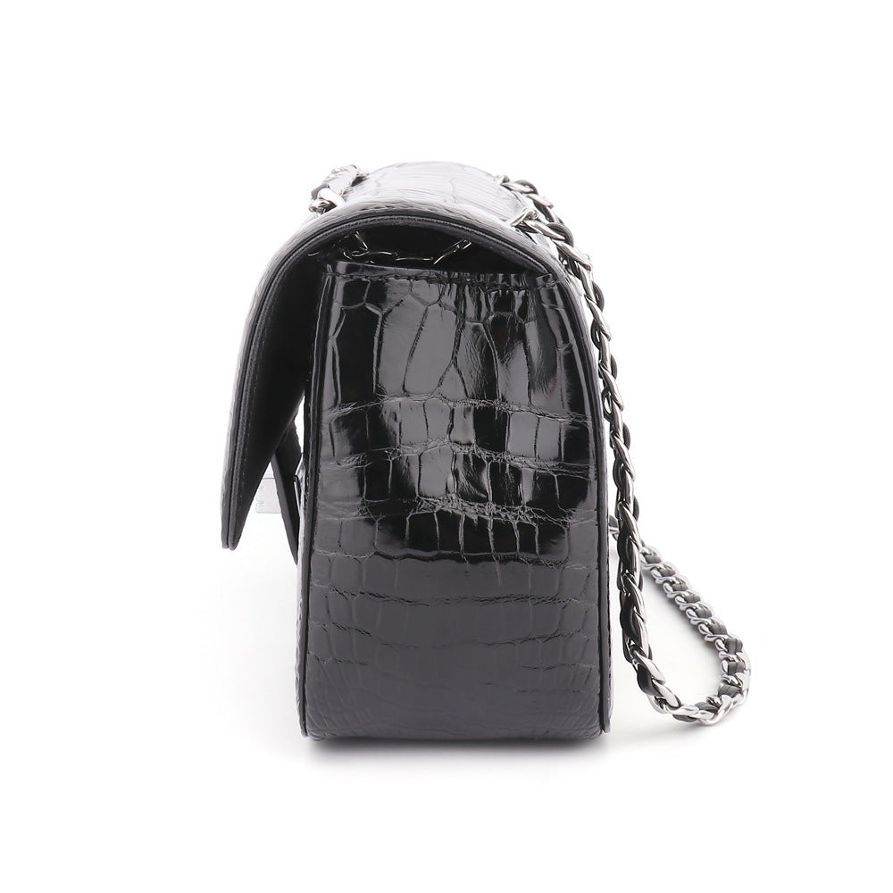Black crocodile-patterned handbag with a chain strap on a white background