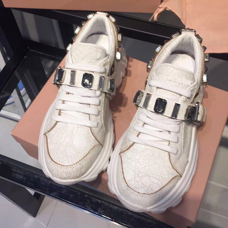 White sneakers with black buckles on a reflective surface