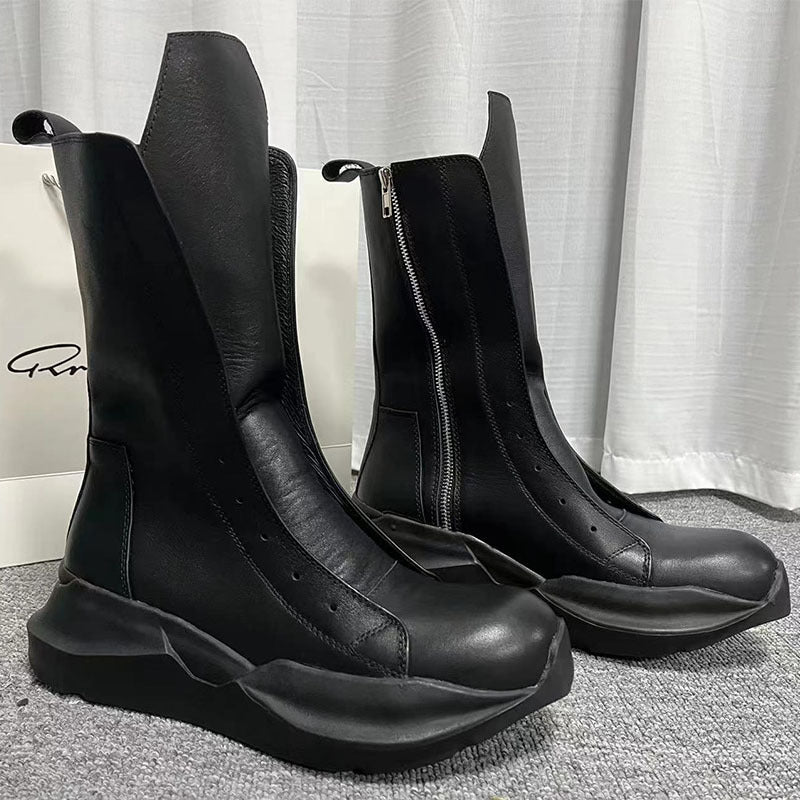 Black leather boots with chunky soles on a gray surface.