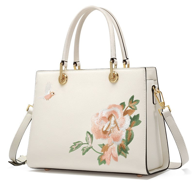 White handbag with floral embroidery on a white background