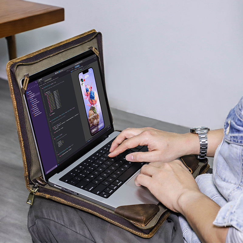 Person using a laptop with a leather case on a table