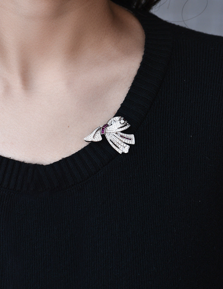 Close-up of a black sweater with a decorative brooch on a neutral background