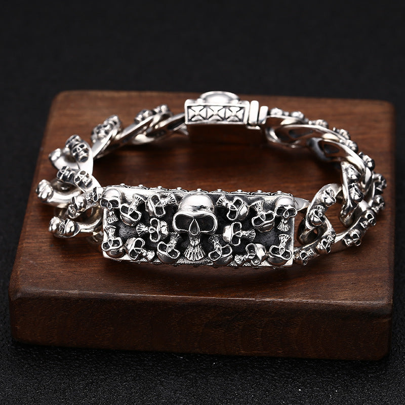 Silver skull-themed bracelet on a wooden block with a dark background