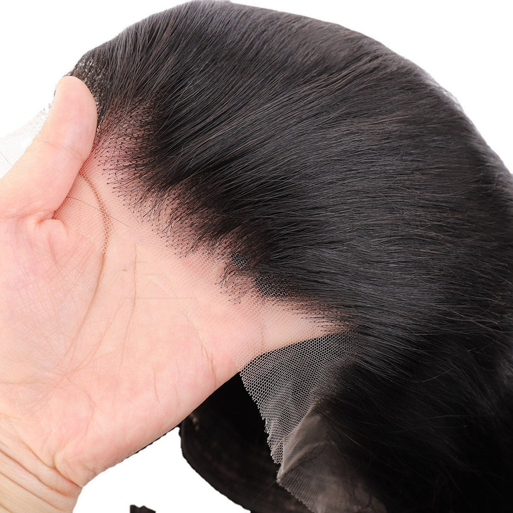 Close-up of a hand holding a black hairpiece against a white background