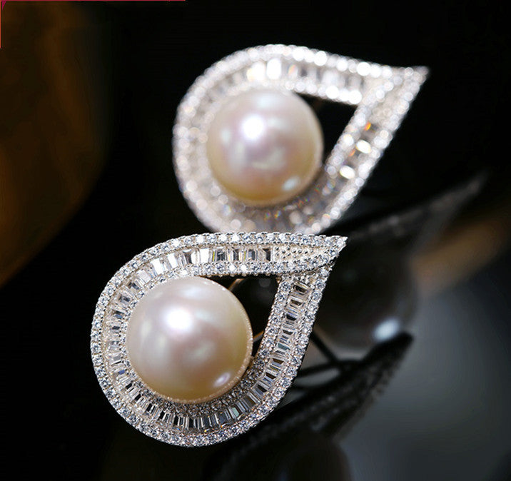 Pearl brooch with silver leaf design on a dark background