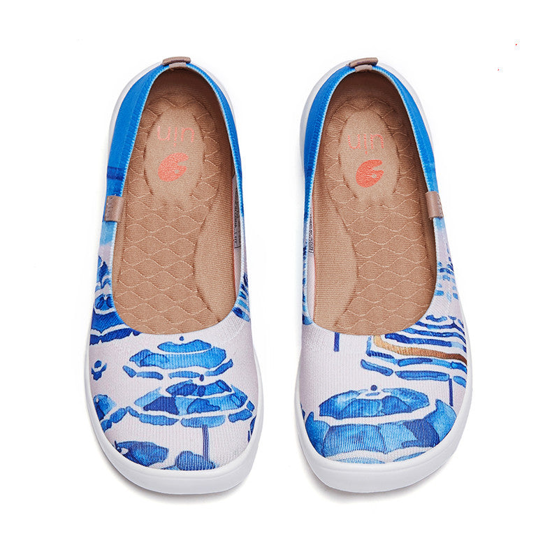 Pair of white slip-on shoes with blue floral pattern on a white background