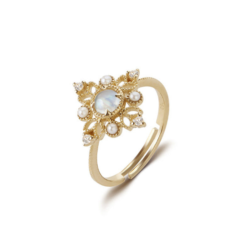 Gold ring with decorative design and pearls on a white background
