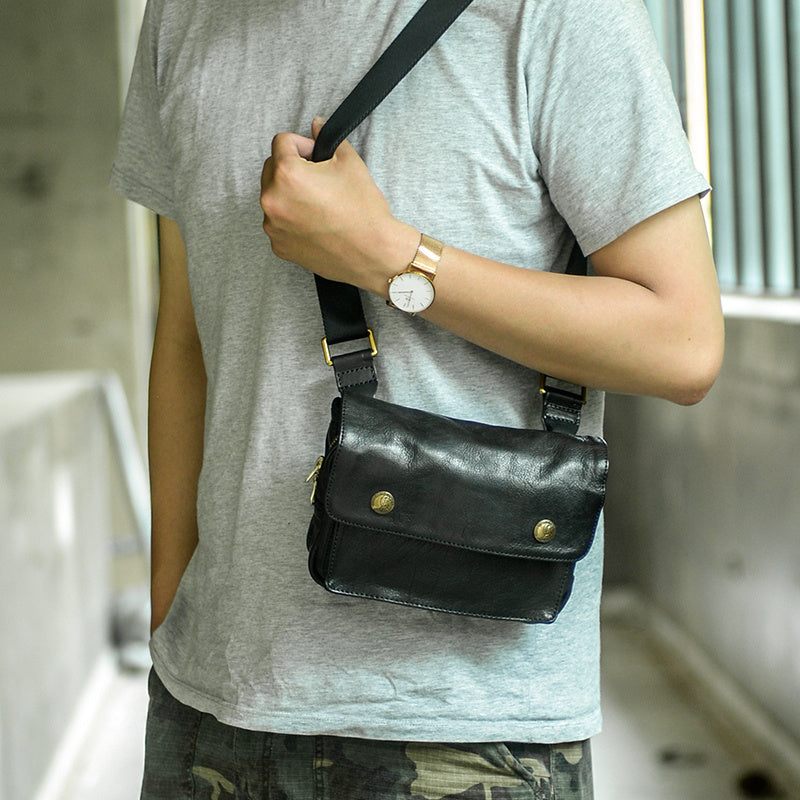 Person wearing a black leather bag over their shoulder with a blurred background