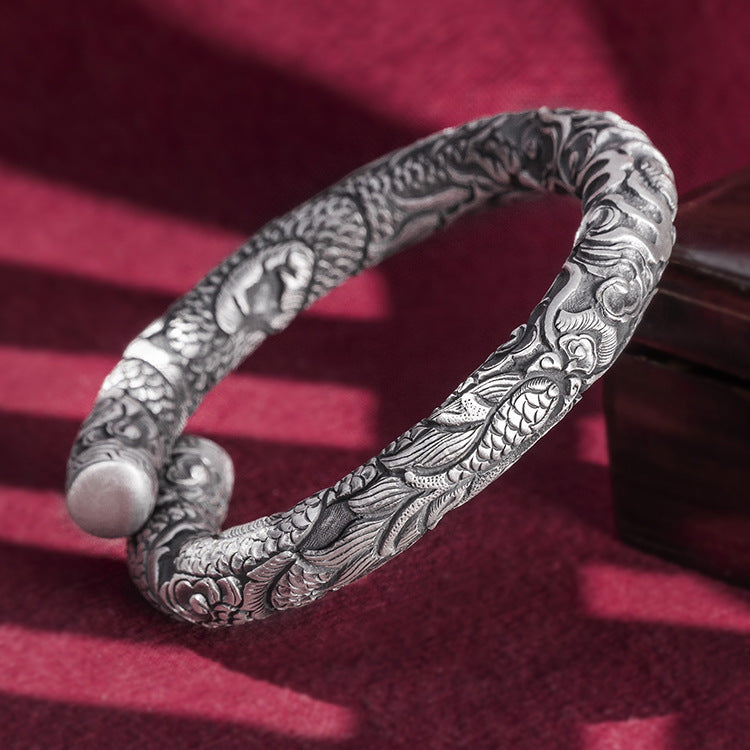 Silver bracelet with intricate designs on a red textured background