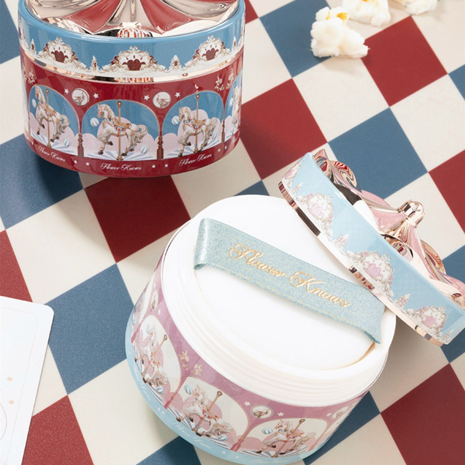 Two decorative jars with carousel horse design on a checkered tablecloth