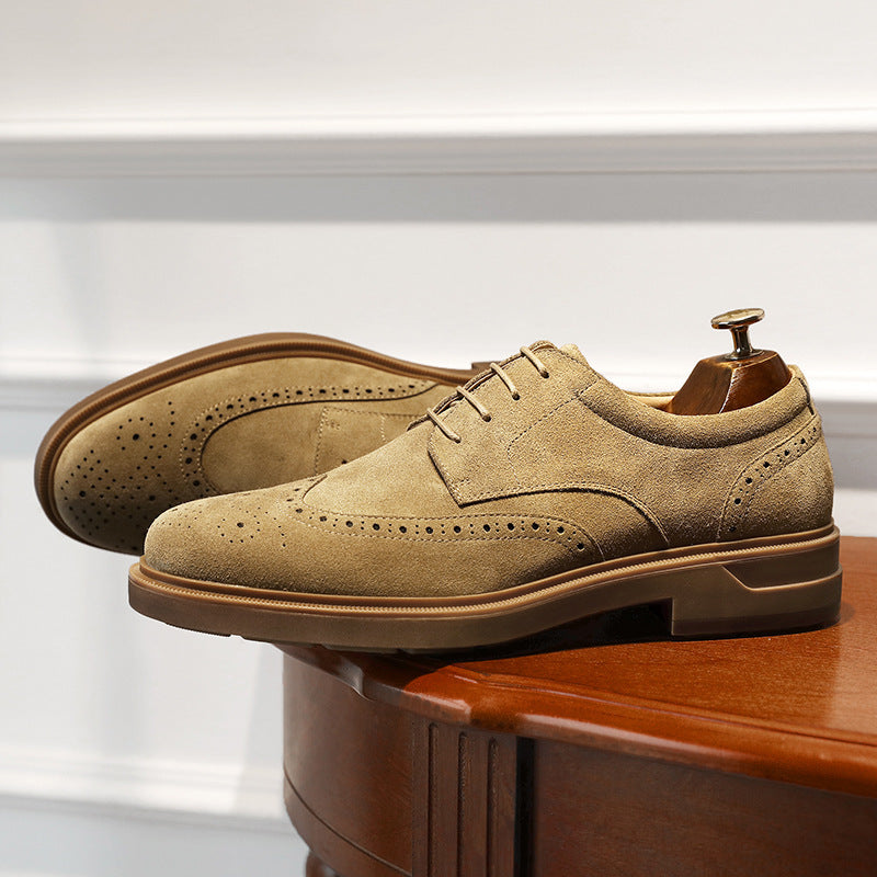Pair of tan suede dress shoes on a wooden surface with a white background