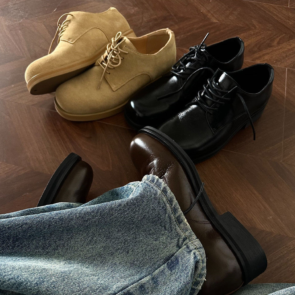 Pair of tan shoes, black shoes, and brown boots on a wooden floor with jeans.