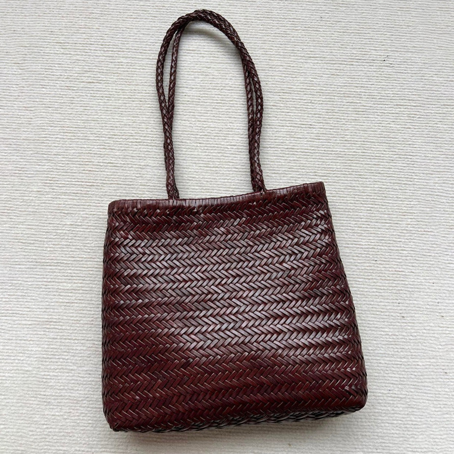 Woven brown handbag on a textured light gray background