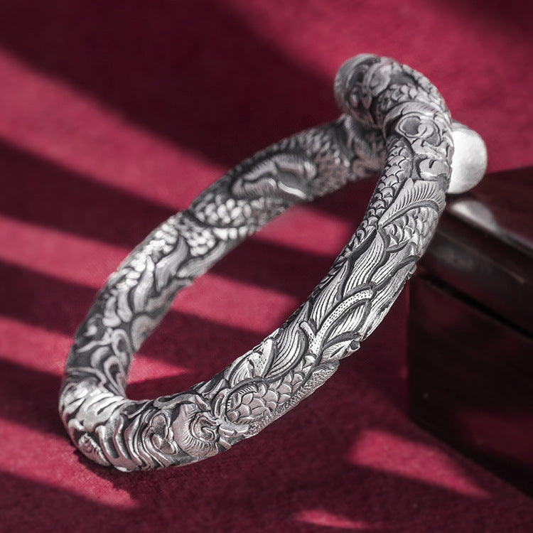 Silver bracelet with intricate designs on a red background